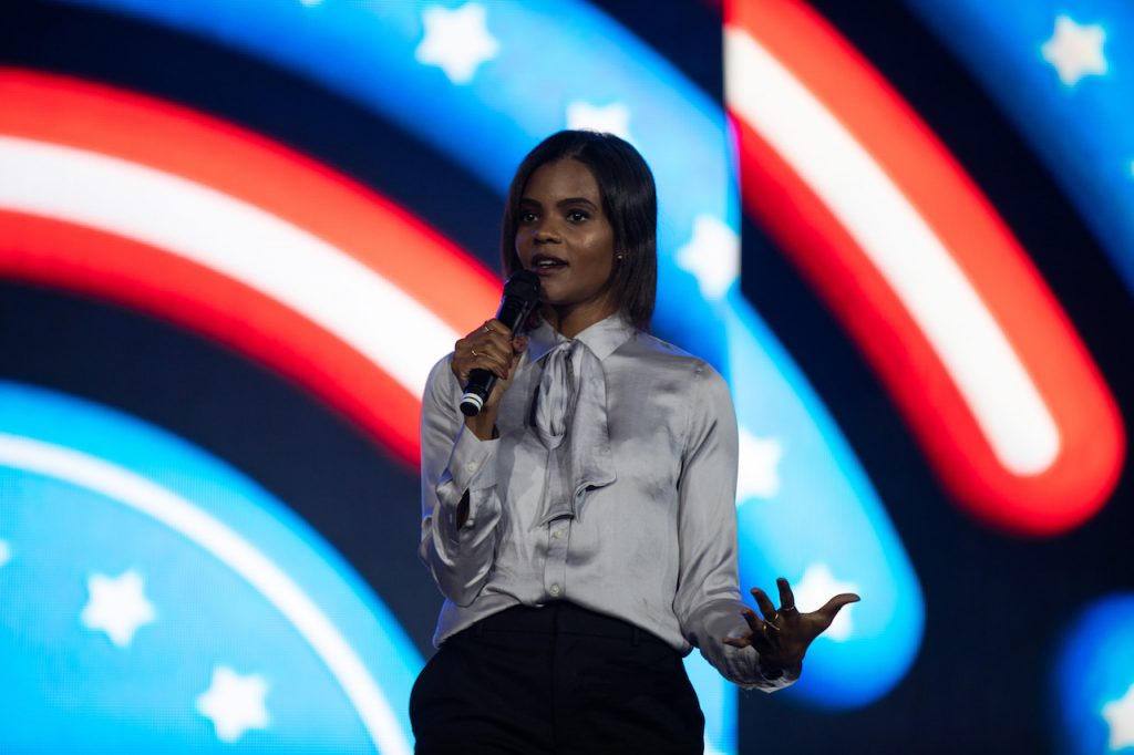 Candace Owens Farmer speaking on stage with an American flag backdrop